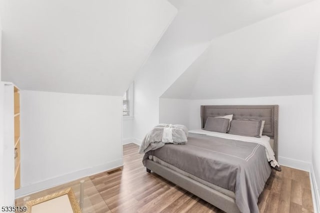 bedroom featuring lofted ceiling and light hardwood / wood-style flooring