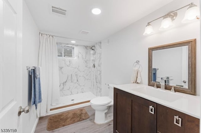 bathroom with walk in shower, vanity, toilet, and hardwood / wood-style floors