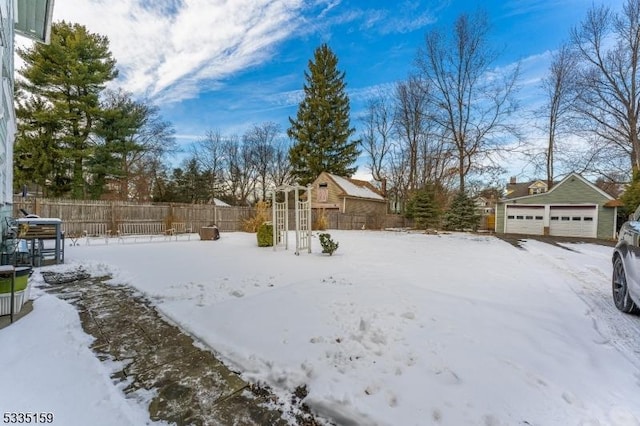 yard layered in snow featuring an outbuilding and a garage