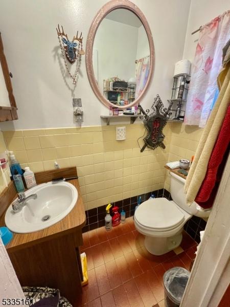 bathroom featuring vanity, tile walls, tile patterned floors, and toilet