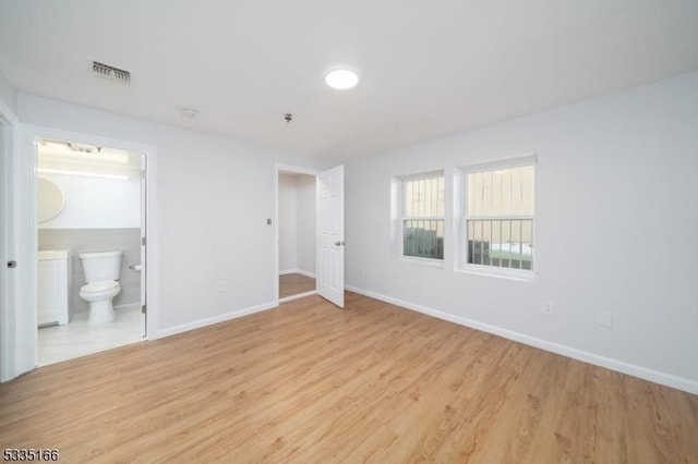 unfurnished bedroom with connected bathroom and light hardwood / wood-style floors