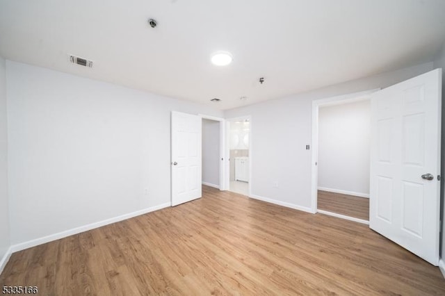 unfurnished bedroom featuring ensuite bathroom and light hardwood / wood-style floors