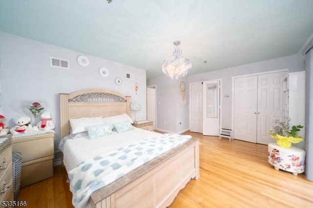 bedroom with an inviting chandelier and light wood-type flooring