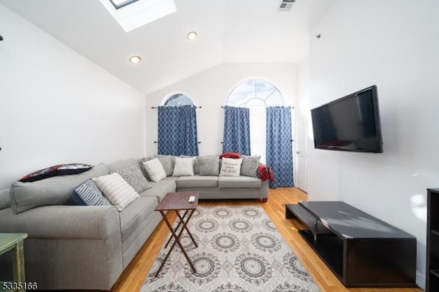 living room featuring lofted ceiling with skylight and light wood-type flooring