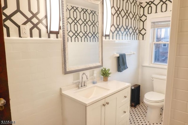 bathroom with vanity, radiator heating unit, tile walls, and toilet