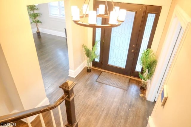 foyer entrance with an inviting chandelier and dark hardwood / wood-style flooring