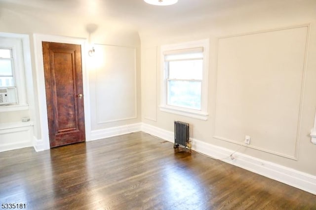 spare room with radiator heating unit and dark hardwood / wood-style flooring