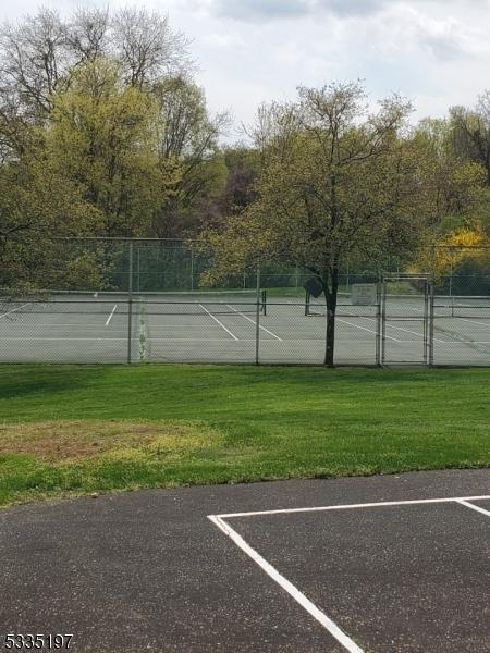 view of tennis court featuring a yard