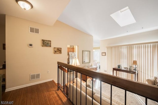 corridor with lofted ceiling with skylight and dark hardwood / wood-style flooring