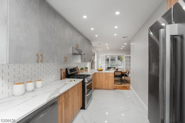 kitchen featuring light stone counters, appliances with stainless steel finishes, and decorative backsplash