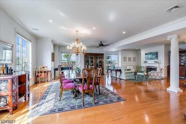 dining space featuring ceiling fan with notable chandelier, ornamental molding, light hardwood / wood-style floors, and ornate columns