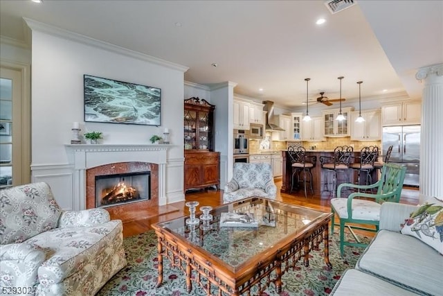 living room with ornate columns, crown molding, and hardwood / wood-style floors