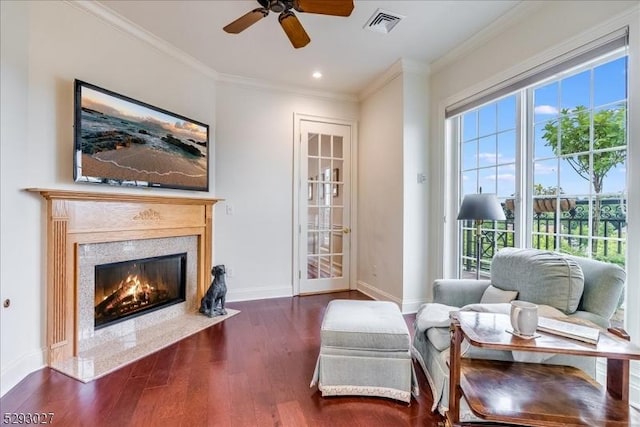 living area featuring dark hardwood / wood-style flooring, ornamental molding, a premium fireplace, and ceiling fan