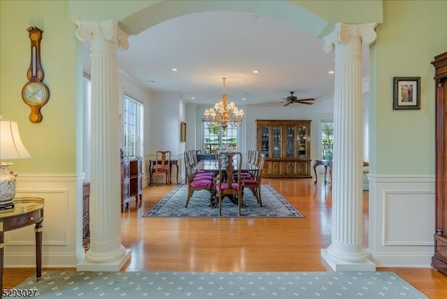 dining area featuring ornamental molding, ceiling fan with notable chandelier, light hardwood / wood-style flooring, and ornate columns