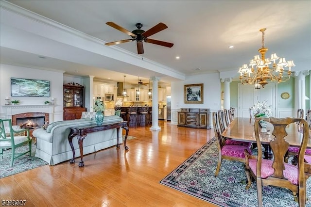 dining room with ornate columns, ornamental molding, ceiling fan, and light hardwood / wood-style flooring