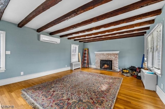 living room with a brick fireplace, beam ceiling, light hardwood / wood-style floors, and a wall mounted AC