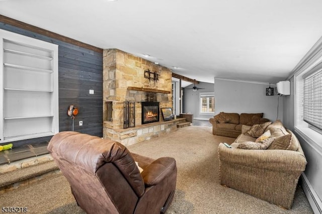 carpeted living room with a stone fireplace, a baseboard radiator, a wall unit AC, built in features, and ceiling fan