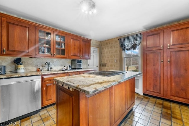 kitchen featuring backsplash, light stone countertops, a kitchen island, stainless steel dishwasher, and cooktop