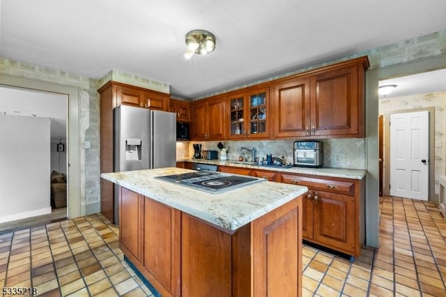 kitchen with light tile patterned floors, backsplash, a center island, light stone countertops, and cooktop