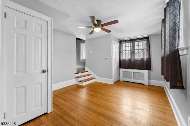 foyer entrance with ceiling fan, radiator, and light wood-type flooring