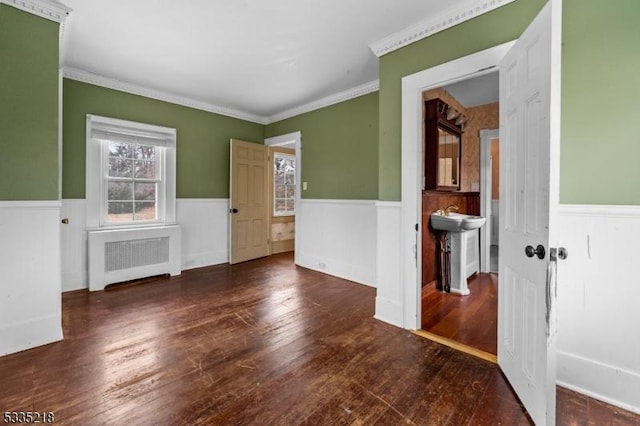 empty room with crown molding, radiator heating unit, and dark hardwood / wood-style flooring