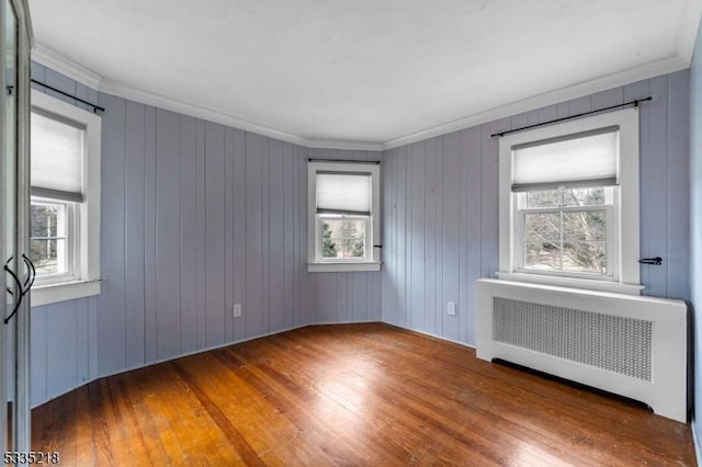 spare room featuring crown molding, a healthy amount of sunlight, radiator heating unit, and dark hardwood / wood-style flooring