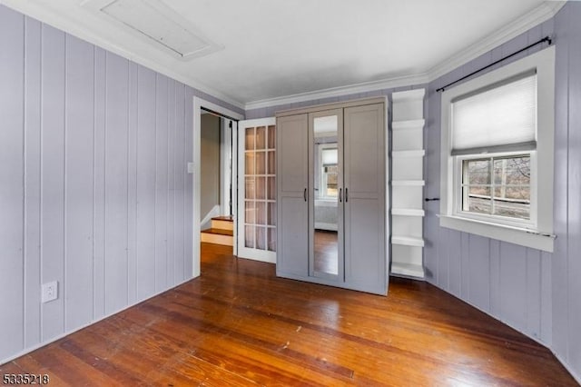 unfurnished bedroom featuring crown molding and dark wood-type flooring