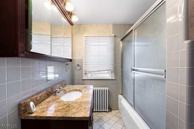 bathroom with radiator, enclosed tub / shower combo, tile walls, vanity, and tile patterned floors