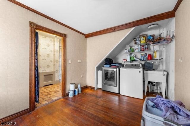 clothes washing area with dark wood-type flooring, ornamental molding, and separate washer and dryer