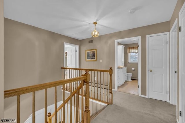 hall with a baseboard heating unit and light colored carpet