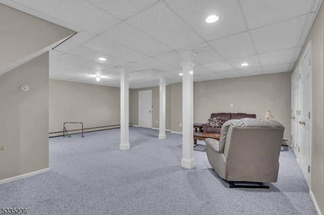 carpeted living room with baseboard heating, decorative columns, and a drop ceiling