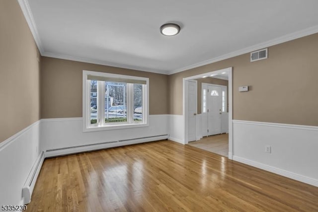 spare room with a baseboard radiator, ornamental molding, and light wood-type flooring