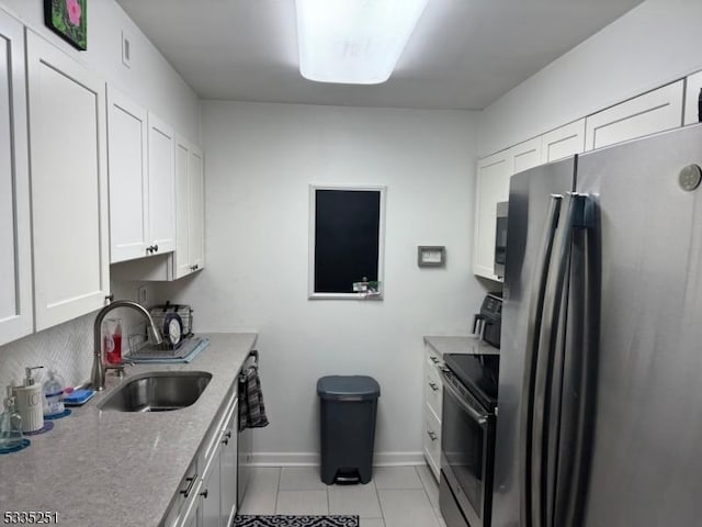 kitchen with sink, light tile patterned floors, stainless steel refrigerator, electric range, and white cabinets