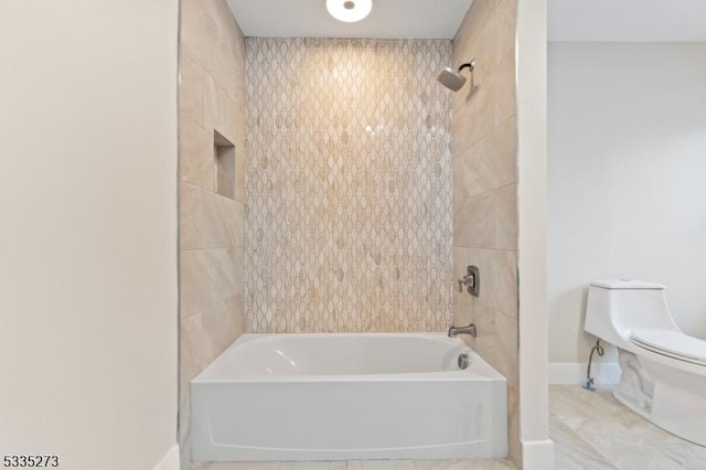 bathroom with tiled shower / bath combo and toilet