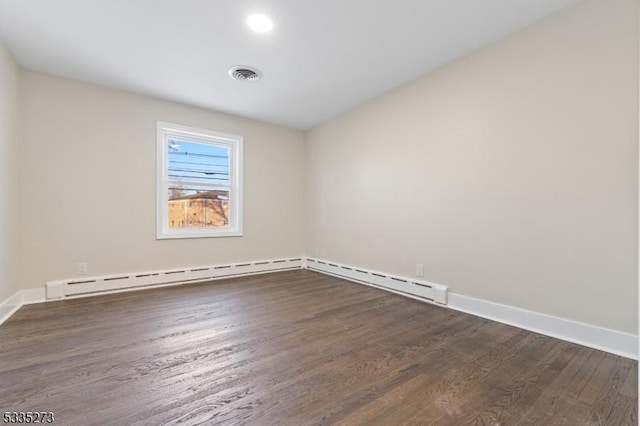 spare room with a baseboard heating unit and dark wood-type flooring