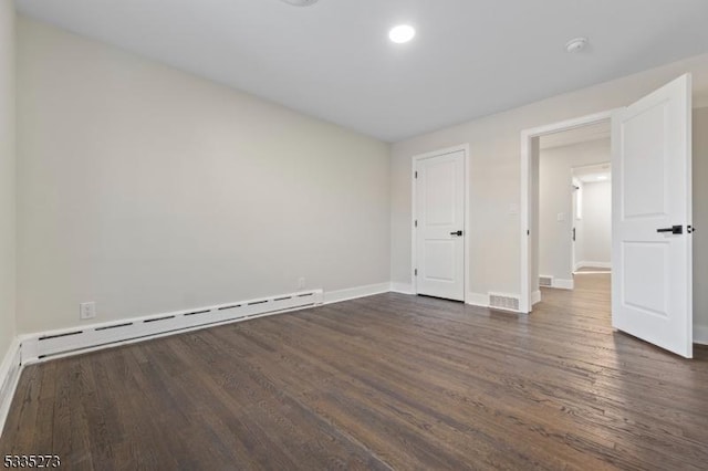 unfurnished bedroom featuring baseboard heating and dark hardwood / wood-style floors