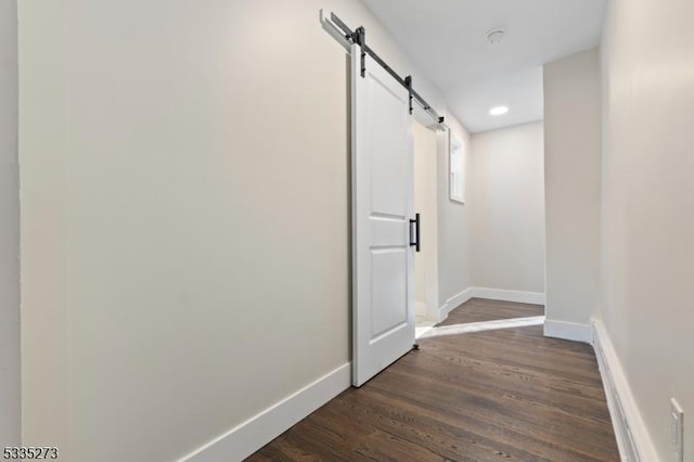 hall with dark wood-type flooring and a barn door