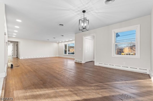 unfurnished living room featuring baseboard heating, dark hardwood / wood-style floors, and a chandelier