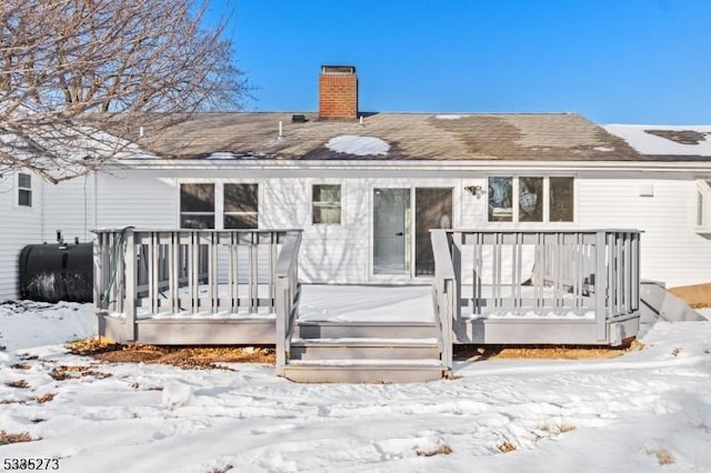 snow covered back of property featuring a wooden deck