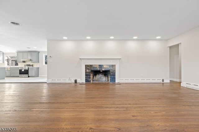 unfurnished living room with a premium fireplace, a baseboard heating unit, and hardwood / wood-style floors