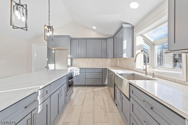 kitchen featuring lofted ceiling, decorative light fixtures, gray cabinets, and sink