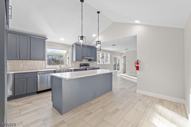 kitchen with pendant lighting, sink, appliances with stainless steel finishes, tasteful backsplash, and a kitchen island