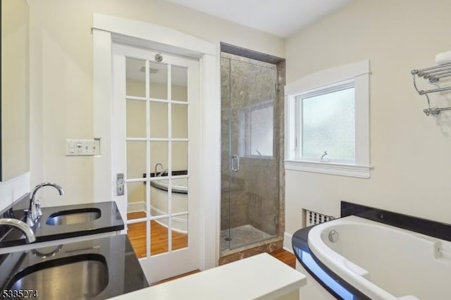 bathroom featuring wood-type flooring, shower with separate bathtub, and sink