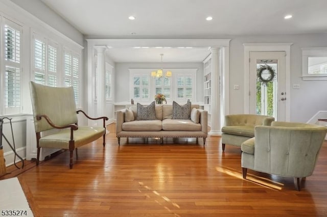 sitting room featuring decorative columns, plenty of natural light, an inviting chandelier, and light hardwood / wood-style floors