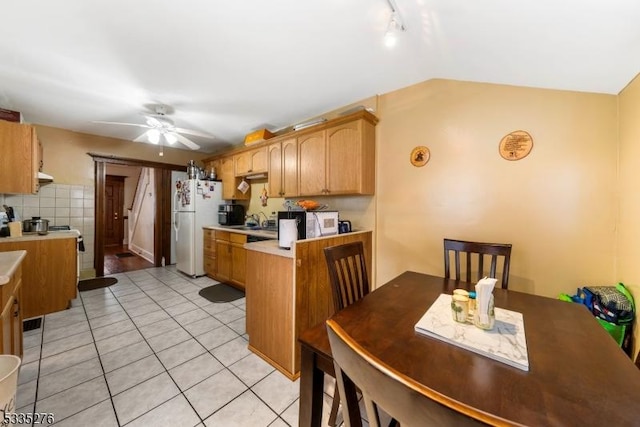 kitchen with lofted ceiling, ceiling fan, tasteful backsplash, light tile patterned flooring, and white fridge