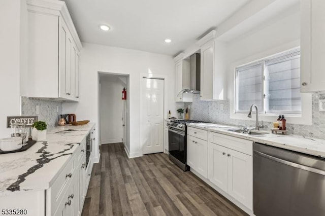 kitchen featuring appliances with stainless steel finishes, sink, white cabinets, and wall chimney exhaust hood