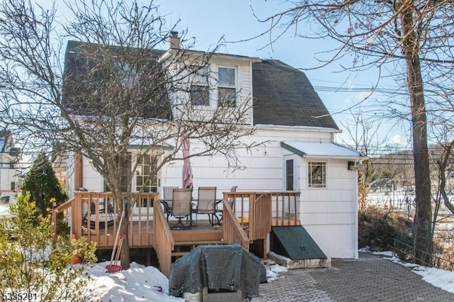 snow covered back of property with a wooden deck