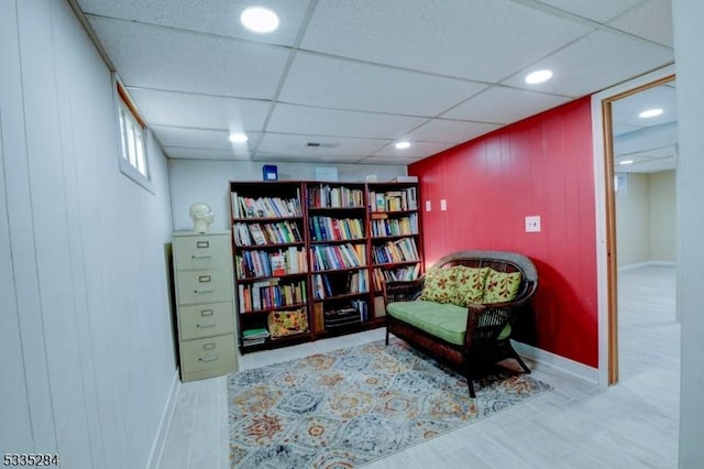 sitting room with a paneled ceiling and wood-type flooring