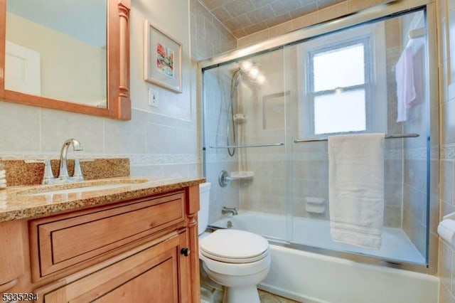 full bathroom with bath / shower combo with glass door, tile walls, decorative backsplash, vanity, and toilet