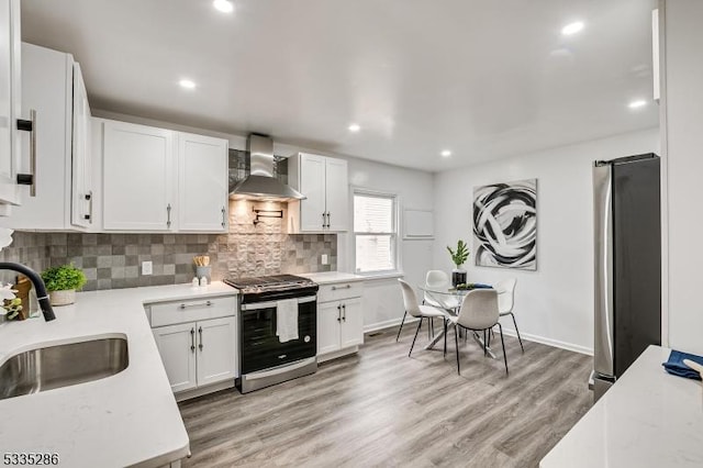 kitchen with wall chimney exhaust hood, sink, appliances with stainless steel finishes, decorative backsplash, and white cabinets